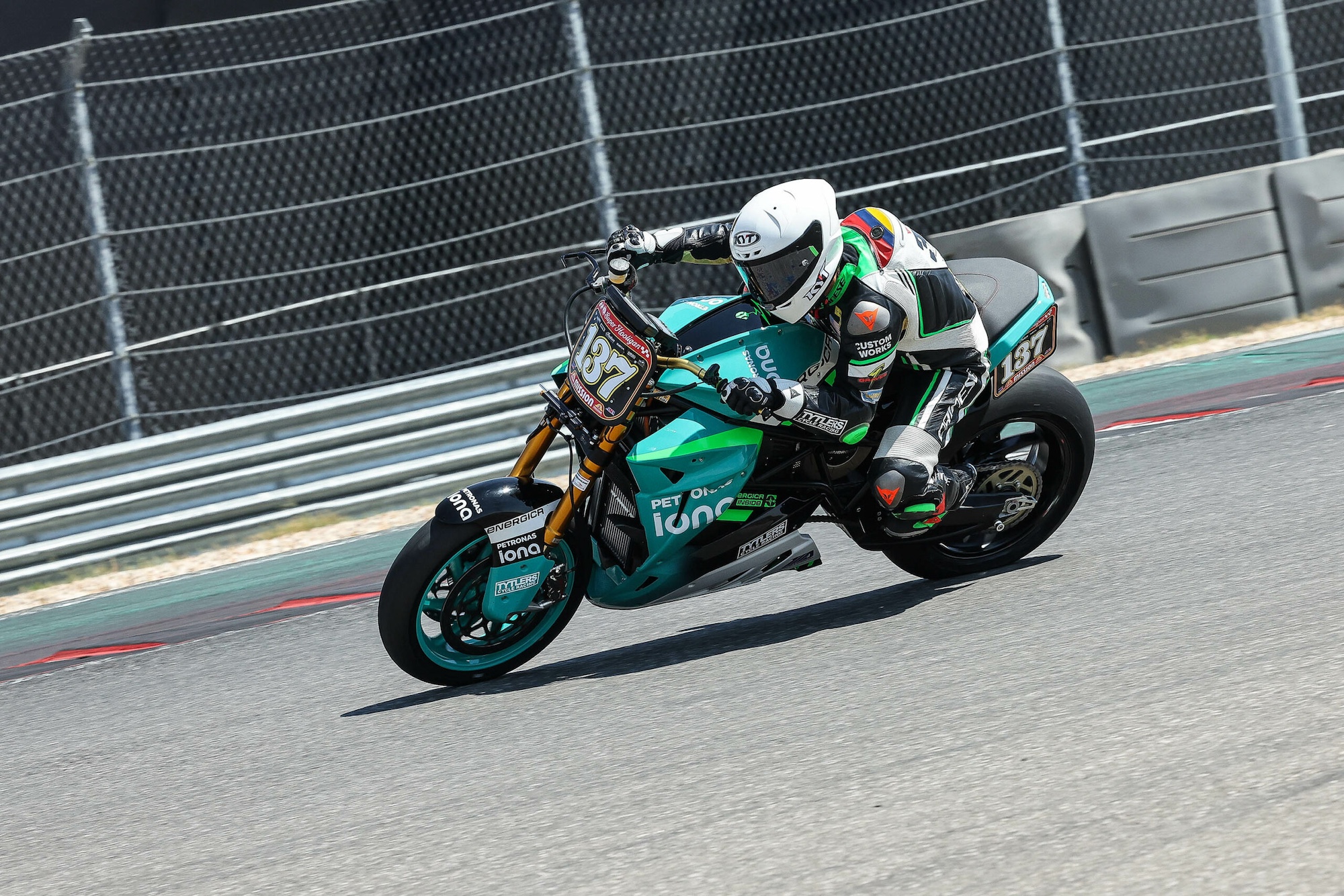 An electric superbike taking the lead on a race track.