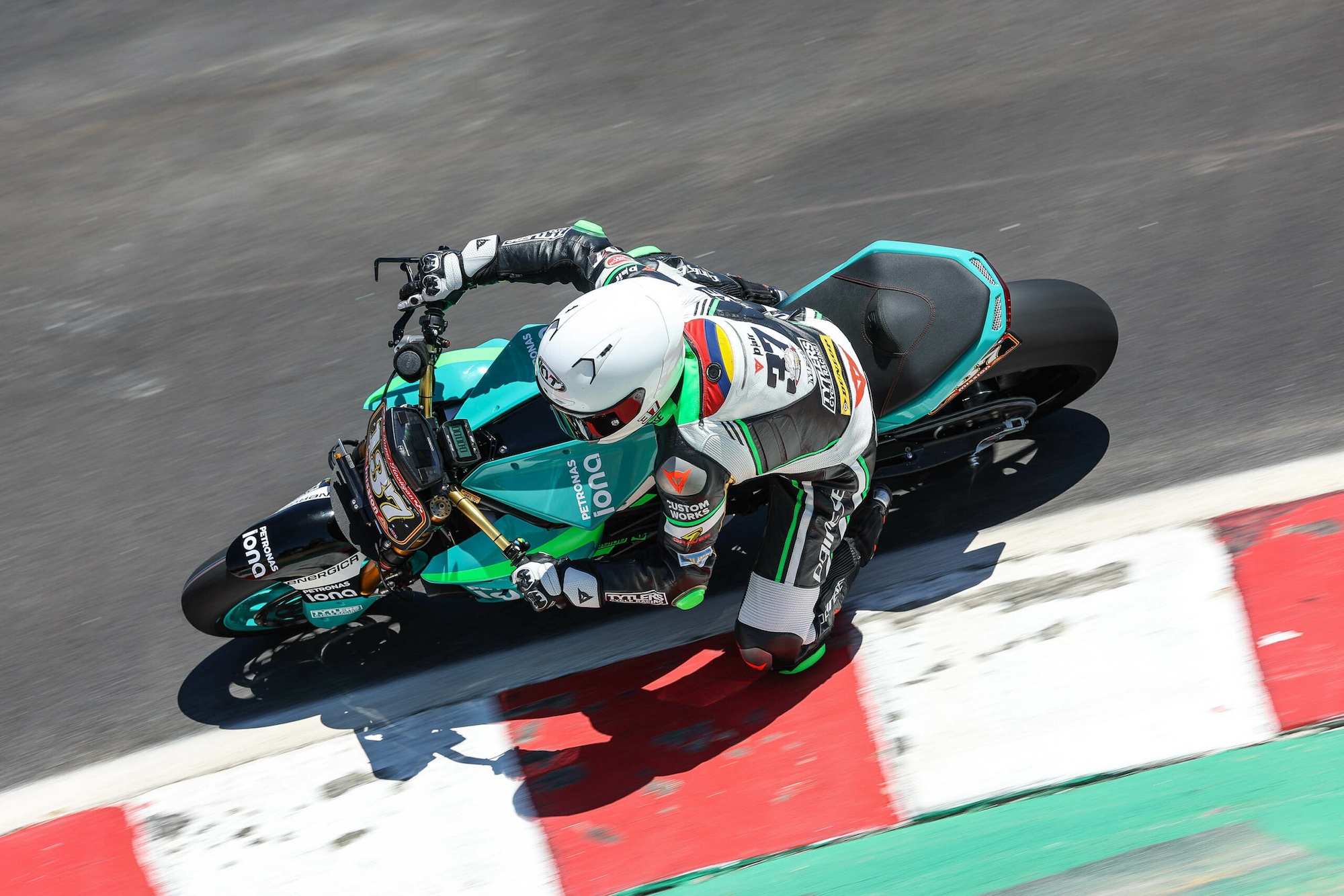 An electric superbike taking the lead on a race track.