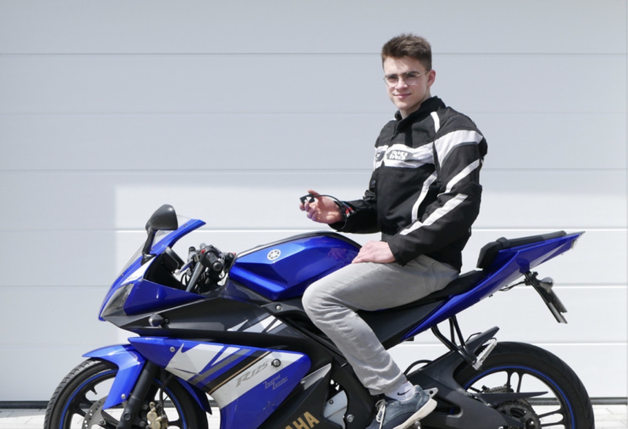 A motorcyclist holding up a device that keeps riders safe.