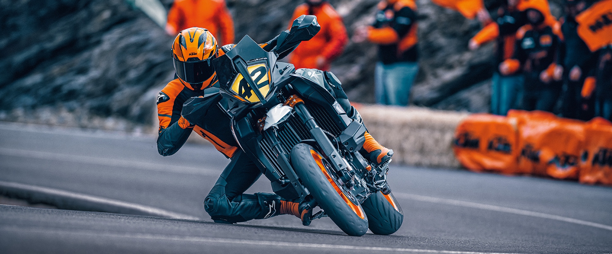 A motorcyclist leaning a Supermoto motorcycle on a road.