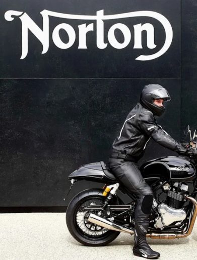 A motorcyclist in front of a sign.