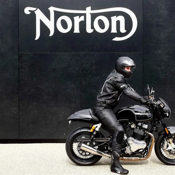 A motorcyclist in front of a sign.