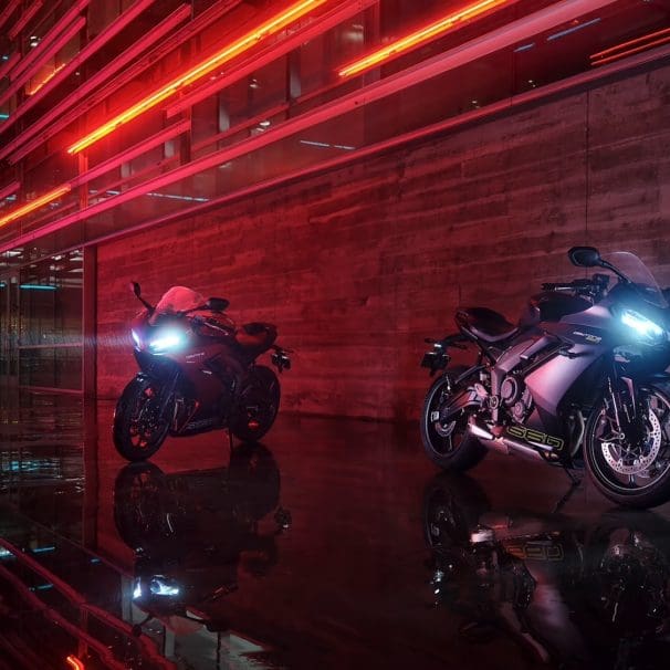 Two Triumph sportbikes parked in front of an urban building.