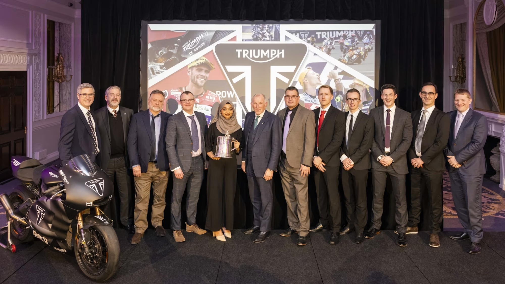 A group of people celebrating Triumph Motorcycles winning an award.