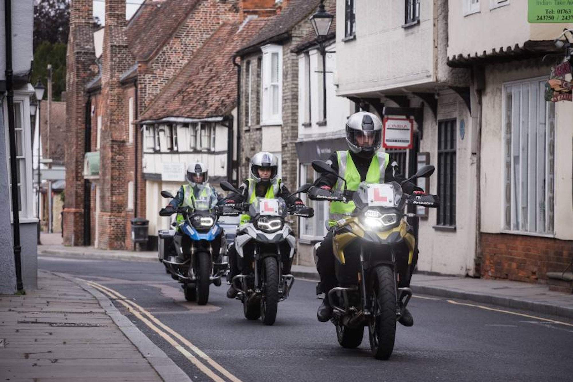 three motorcyclists riding down a street.