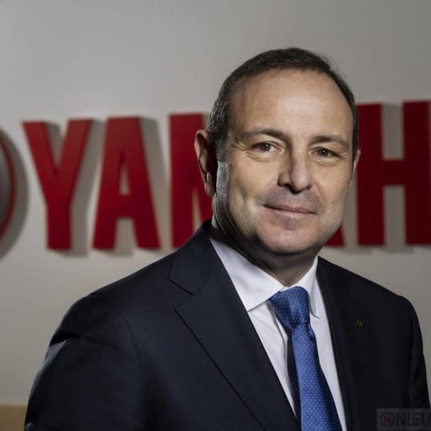 A man in a suit in front of a logo.