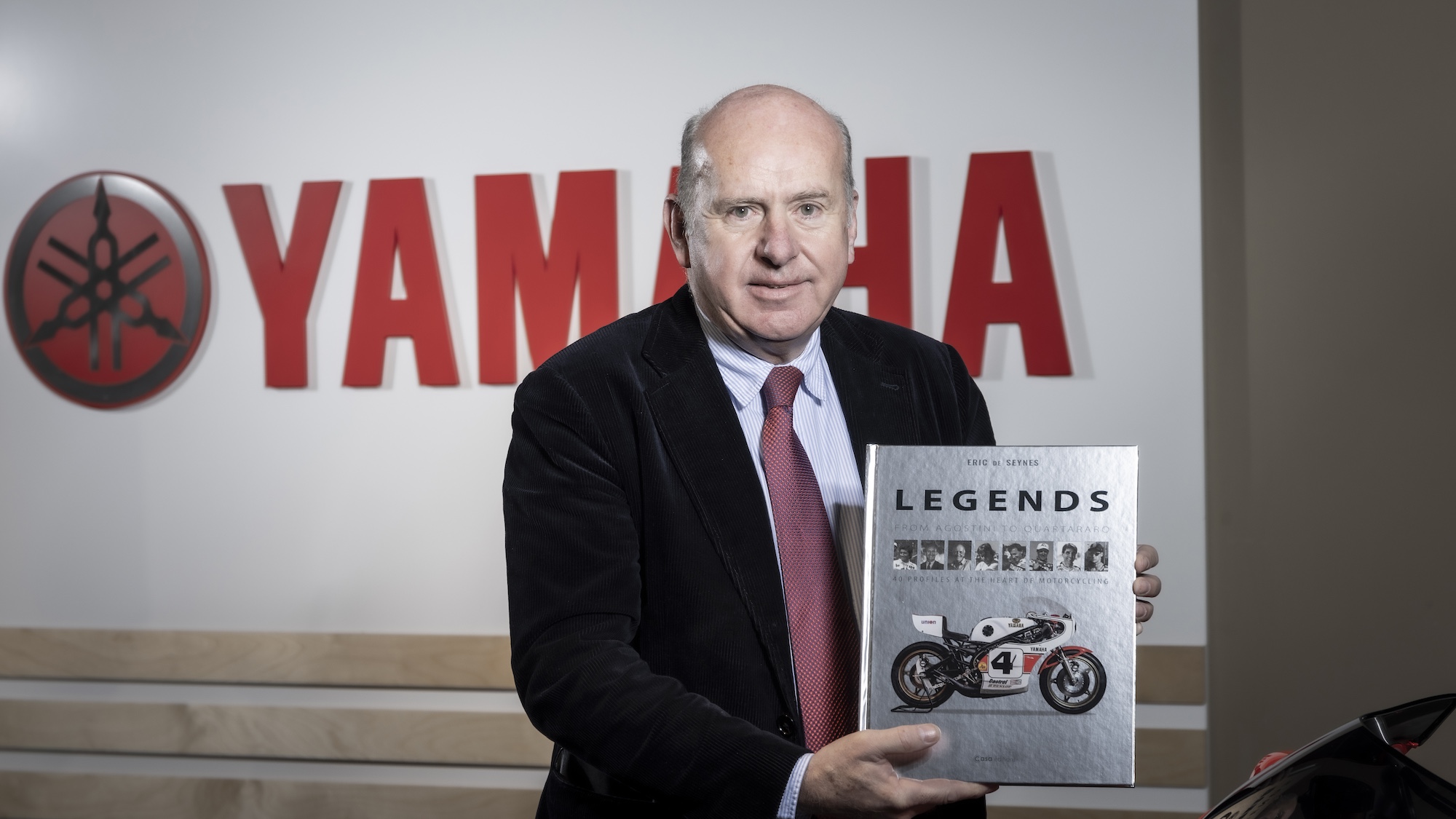 A man holding a book in front of a Yamaha sign.