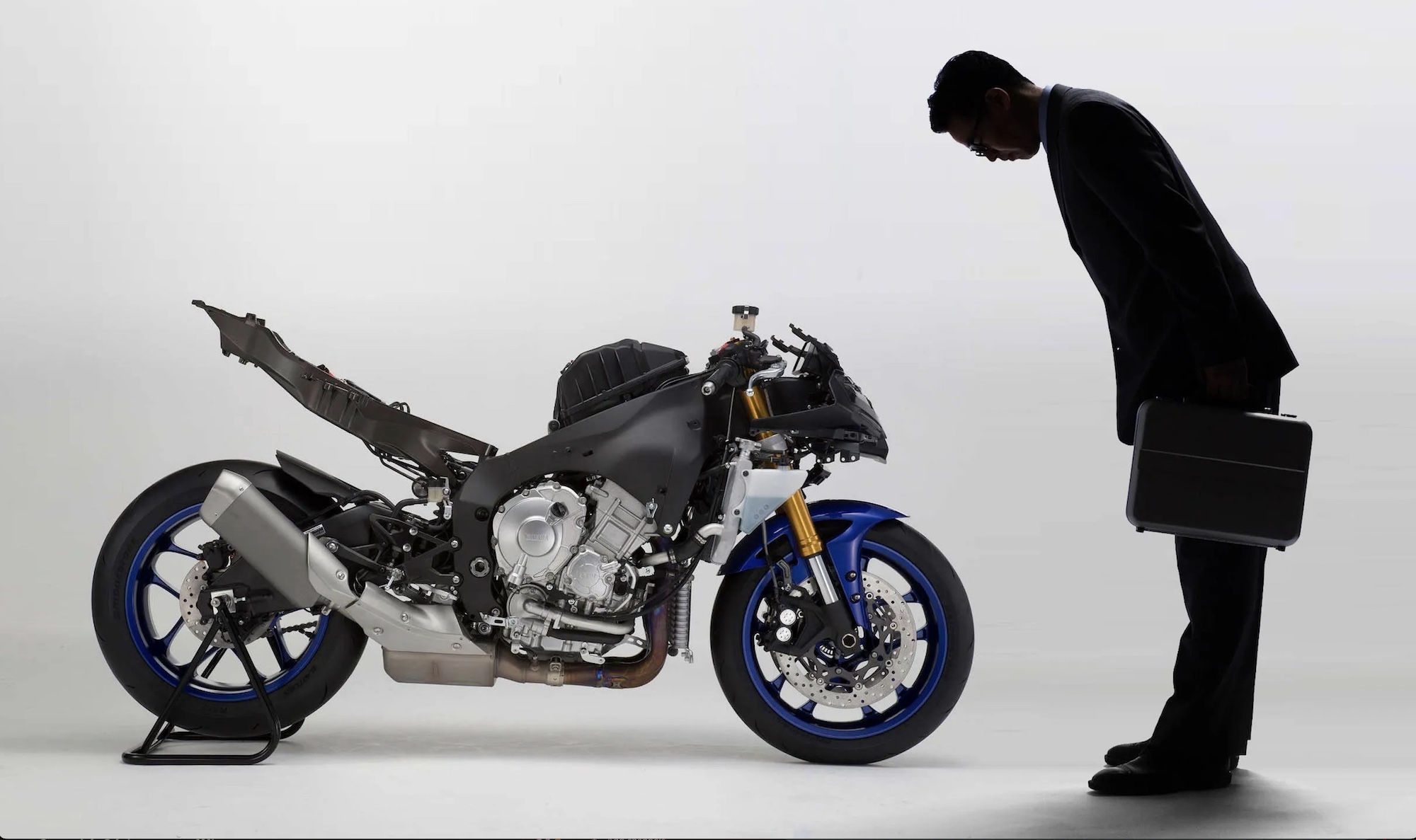 A man bowing to a stripped motorcycle .