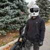 Front view of Devan wearing the Defender Motorcycle Hoodie in front of a Harley