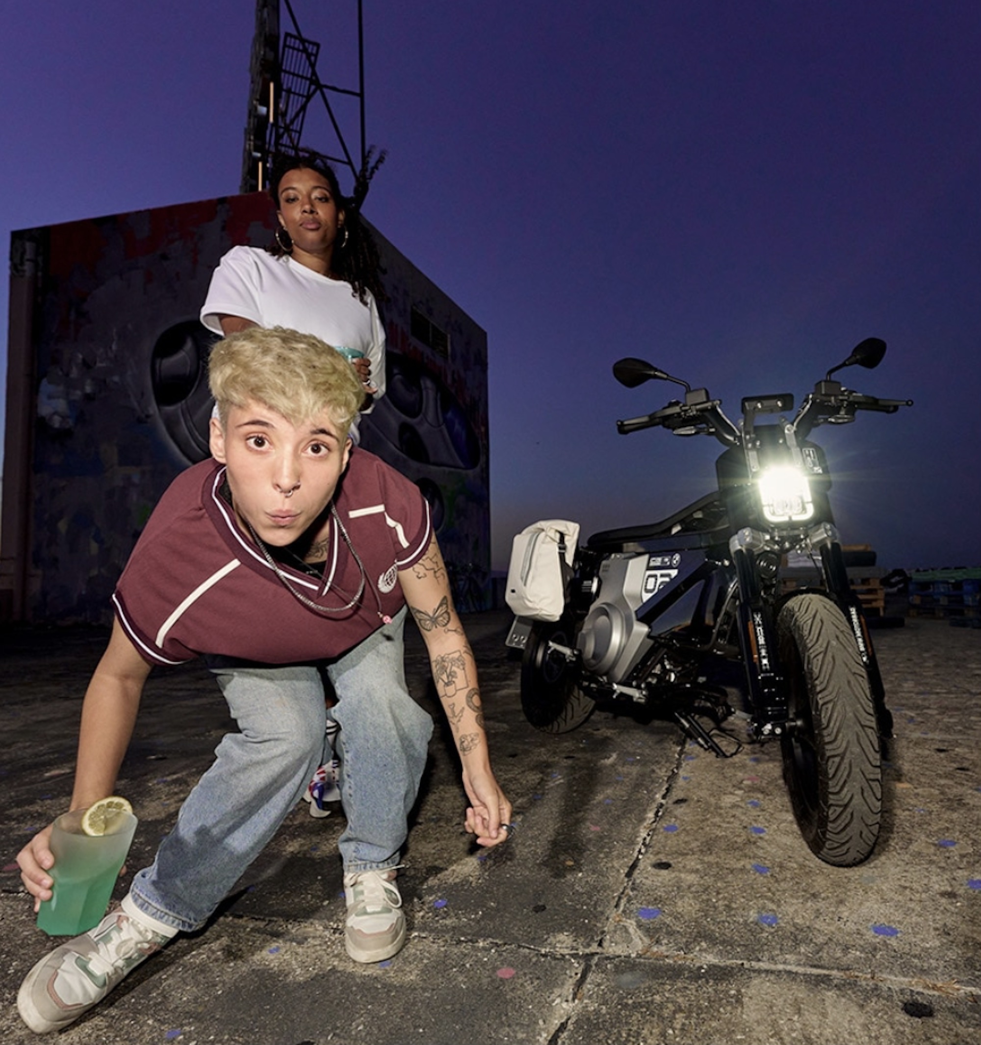 two teens next to an electric motorcycle.