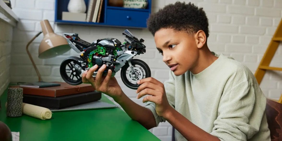 A boy holding a LEGO motorcycle.