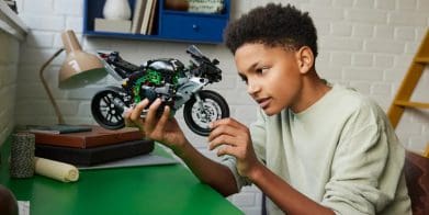 A boy holding a LEGO motorcycle.