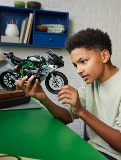 A boy holding a LEGO motorcycle.