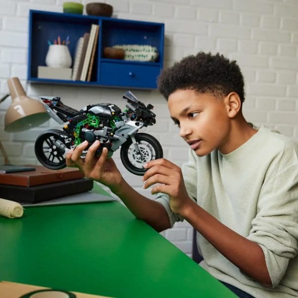A boy holding a LEGO motorcycle.
