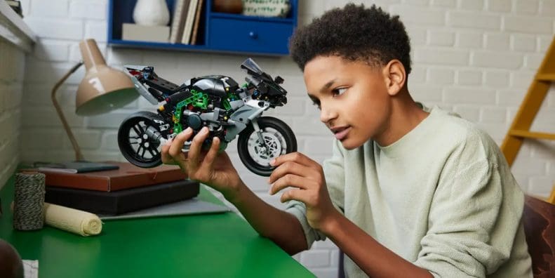 A boy holding a LEGO motorcycle.