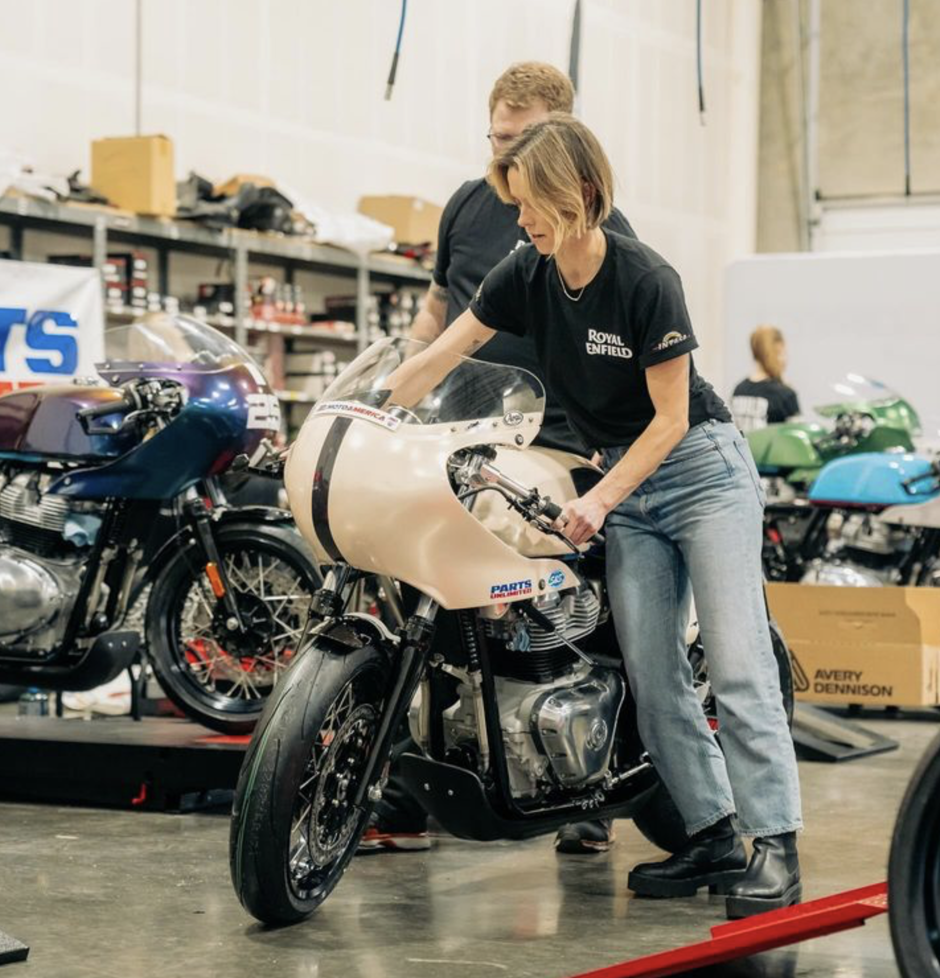 A girl rolling out a motorcycle.