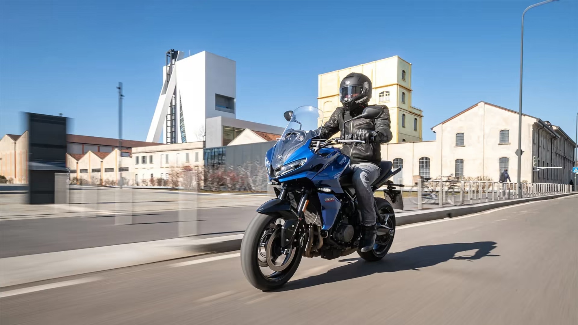 A motorcyclist on a blue bike in the city.