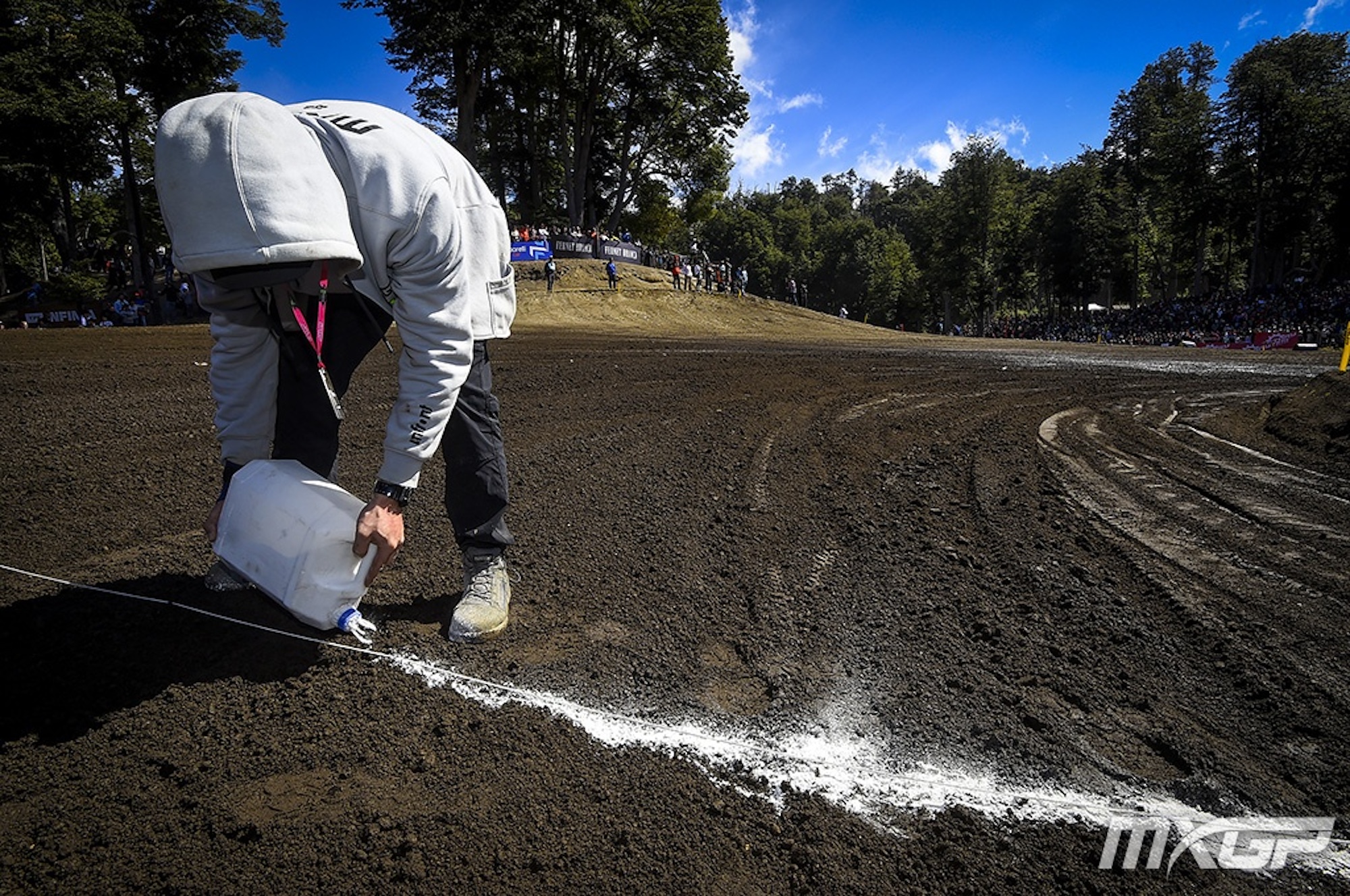 A man laying chalk down to create a finish line in a motorcycle race.