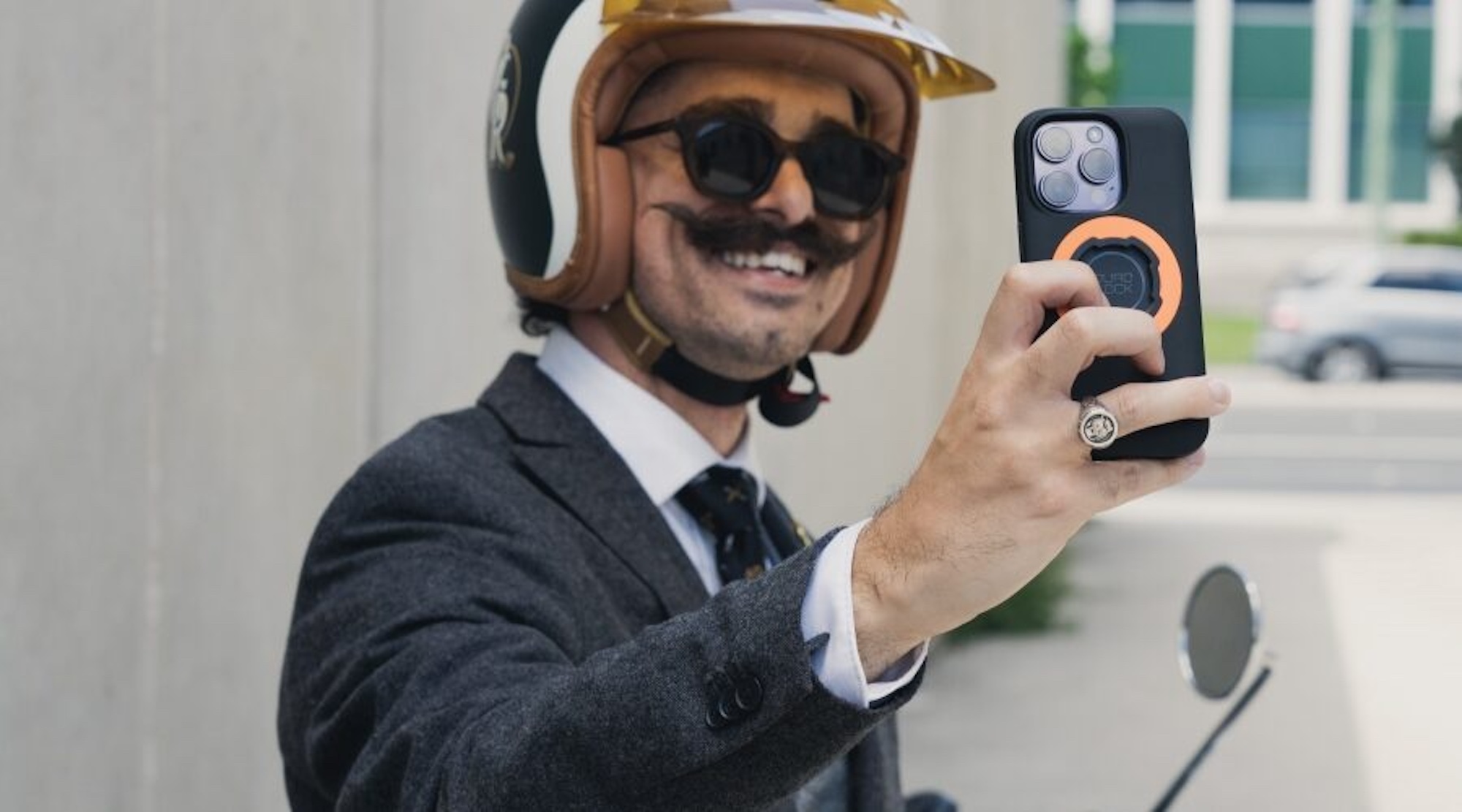 A ma with a moustache taking a selfie.