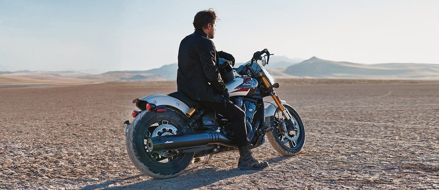 A man on a motorcycle in the desert.