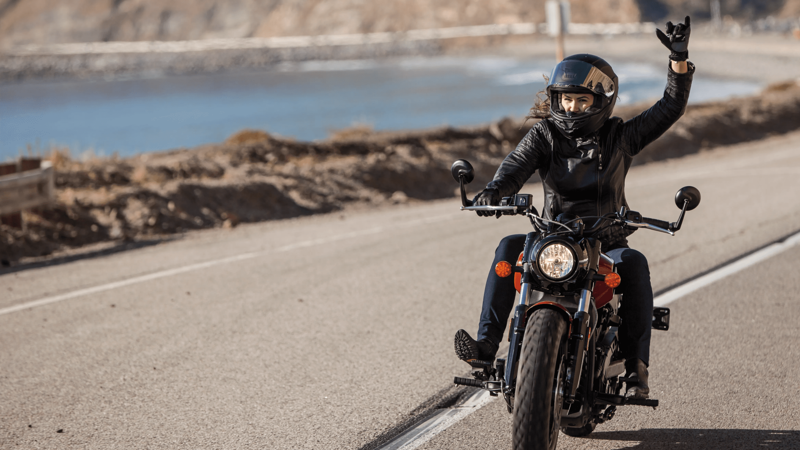 Female motorcyclist cruising on a coastal road